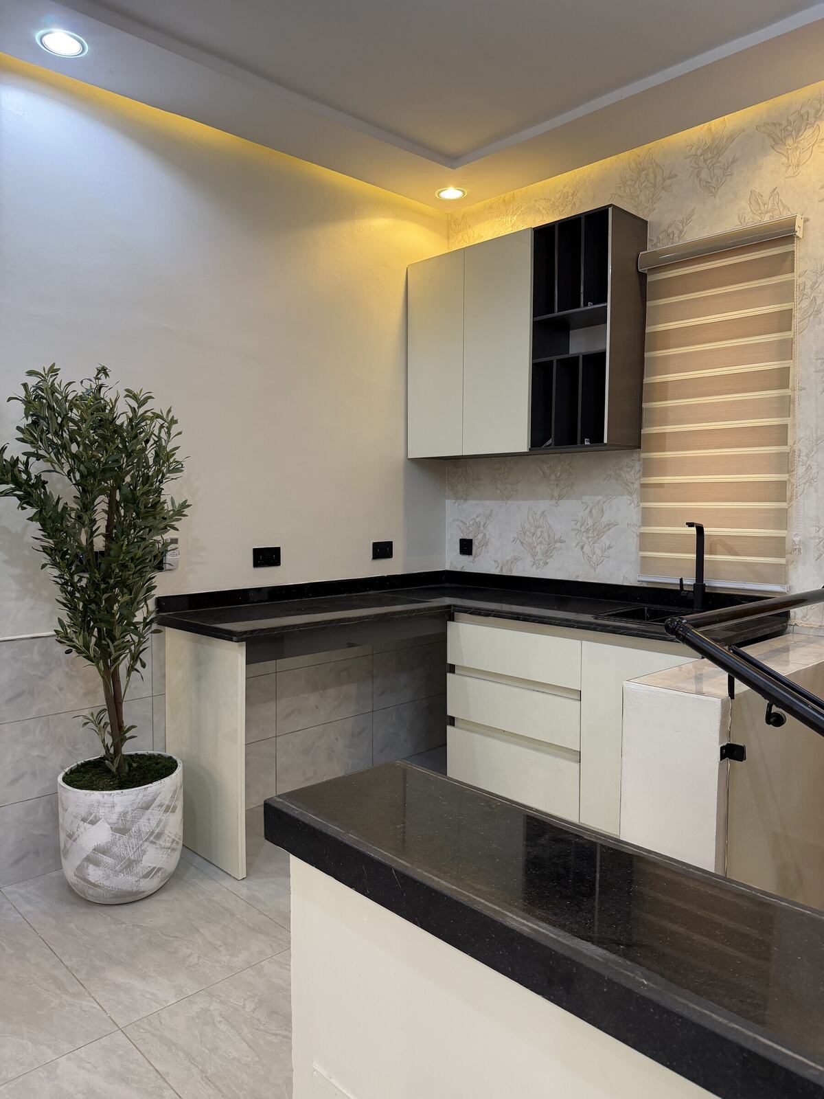 Kitchen with cream cabinetry and black countertops